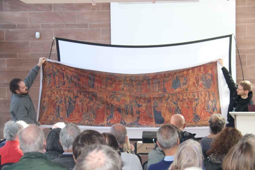 Volunteers holding up a replica of the Guildhall tapestry