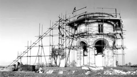 Old black and whilte photograph of the windmill tower in scaffolding.